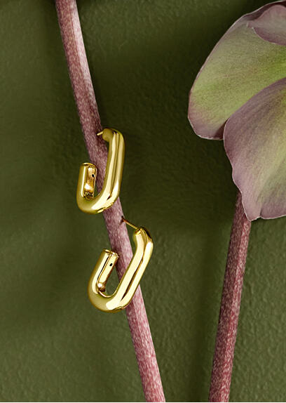 Yellow gold hoop earrings suspended by the stem of a blooming plant.