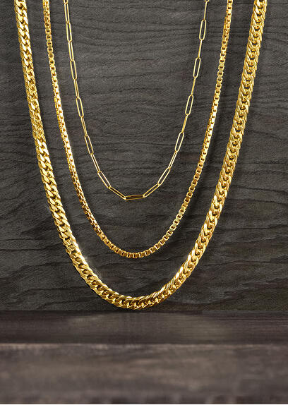 Three yellow gold necklaces on a wooden surface.