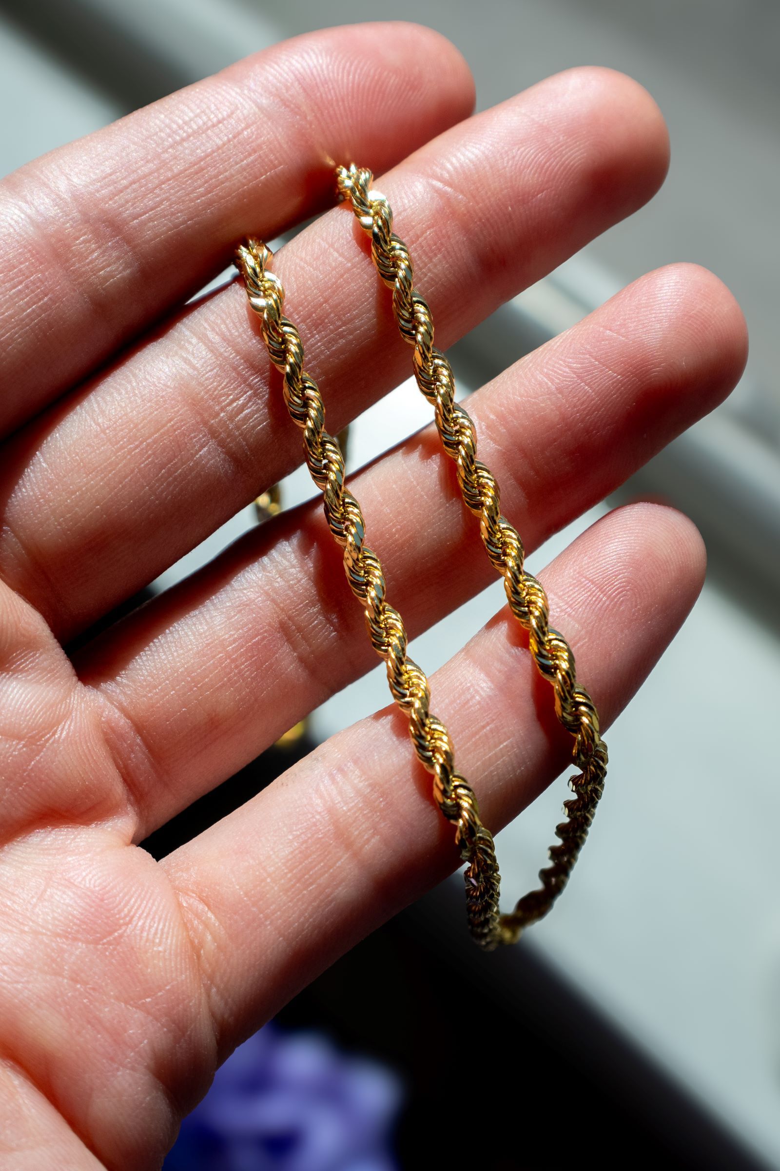 Yellow gold rope chain shines in the palm of someone's hand Yellow gold rope chain shines in the palm of someone's hand