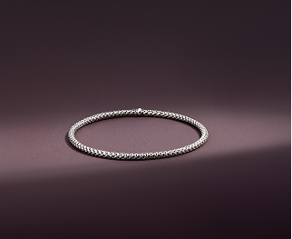 Sterling silver Toscano bracelet is shown in a stream of light on a smooth purple surface amid two shadows