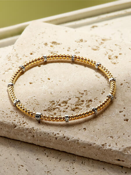 A 14k yellow gold bracelet with diamond stations set in white gold.