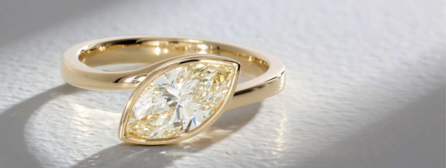 Solitaire marquise diamond ring with a bezel setting of 14k yellow gold.