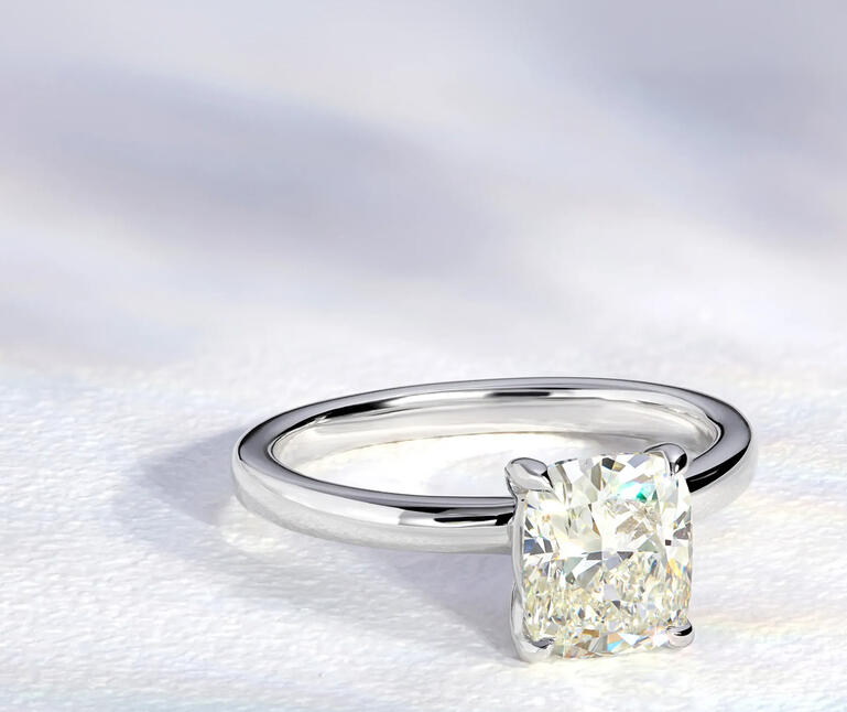 Cushion cut solitaire diamond engagement ring in white gold.