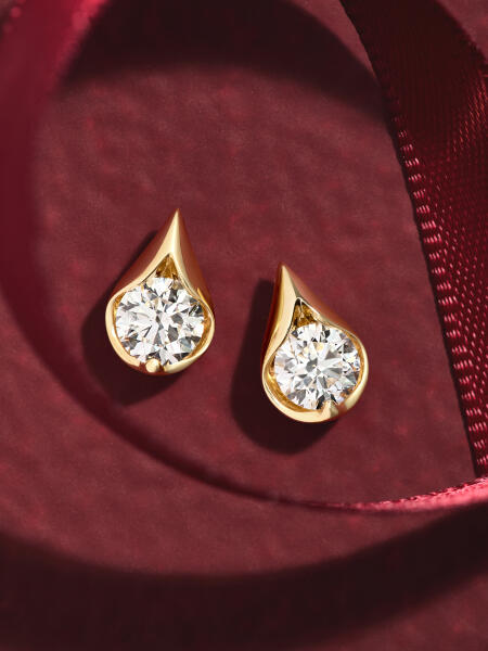 Round diamond stud earrings in a teardrop setting of yellow gold.
