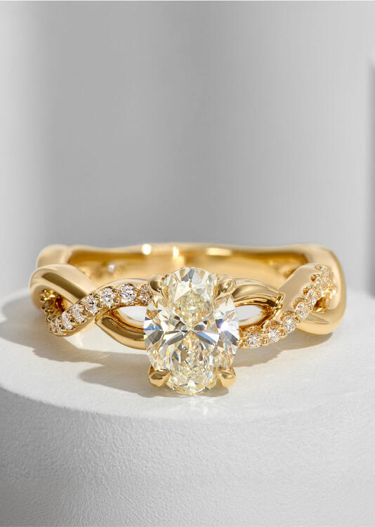 An oval diamond engagement ring with a twisted shank and round accent diamonds.