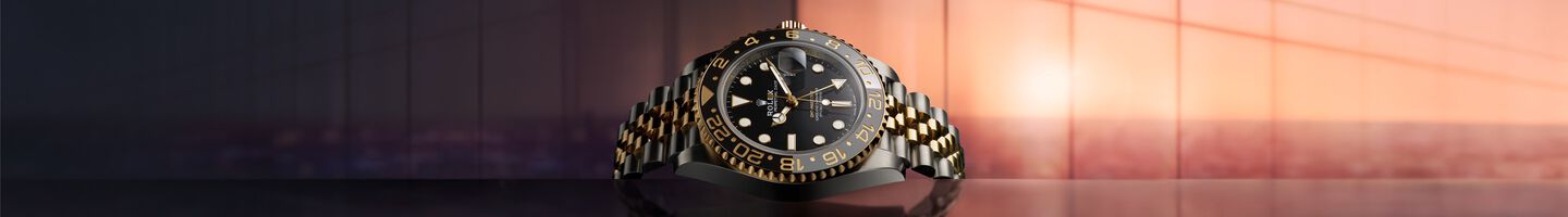 Rolesor Rolex GMT-Master II with black dial against a setting sun background. 