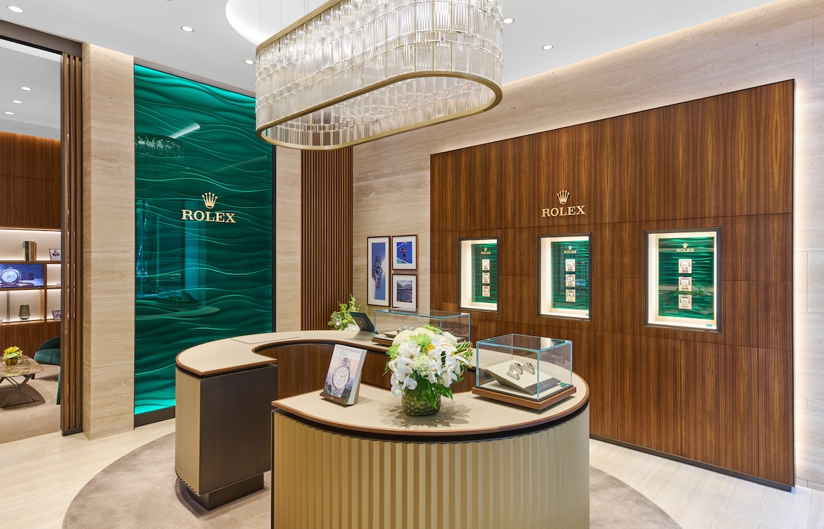 In a wood paneled interior of a Portland Rolex showroom, a watch display showcases iconic Rolex models.
